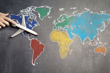 Comprehensive Guide. - Top view of crop anonymous person holding toy airplane on colorful world map drawn on chalkboard