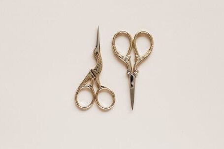 Affiliate Toolkit - Top view composition of scissors of various shape with carved ornament on beige table