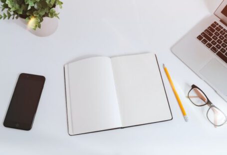 Affiliate Marketing - An open empty notebook on a white desk next to an iPhone and a MacBook