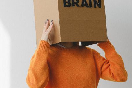 Commissions, Understanding - Crop person putting Idea title in cardboard box with Brain inscription on head of female on light background